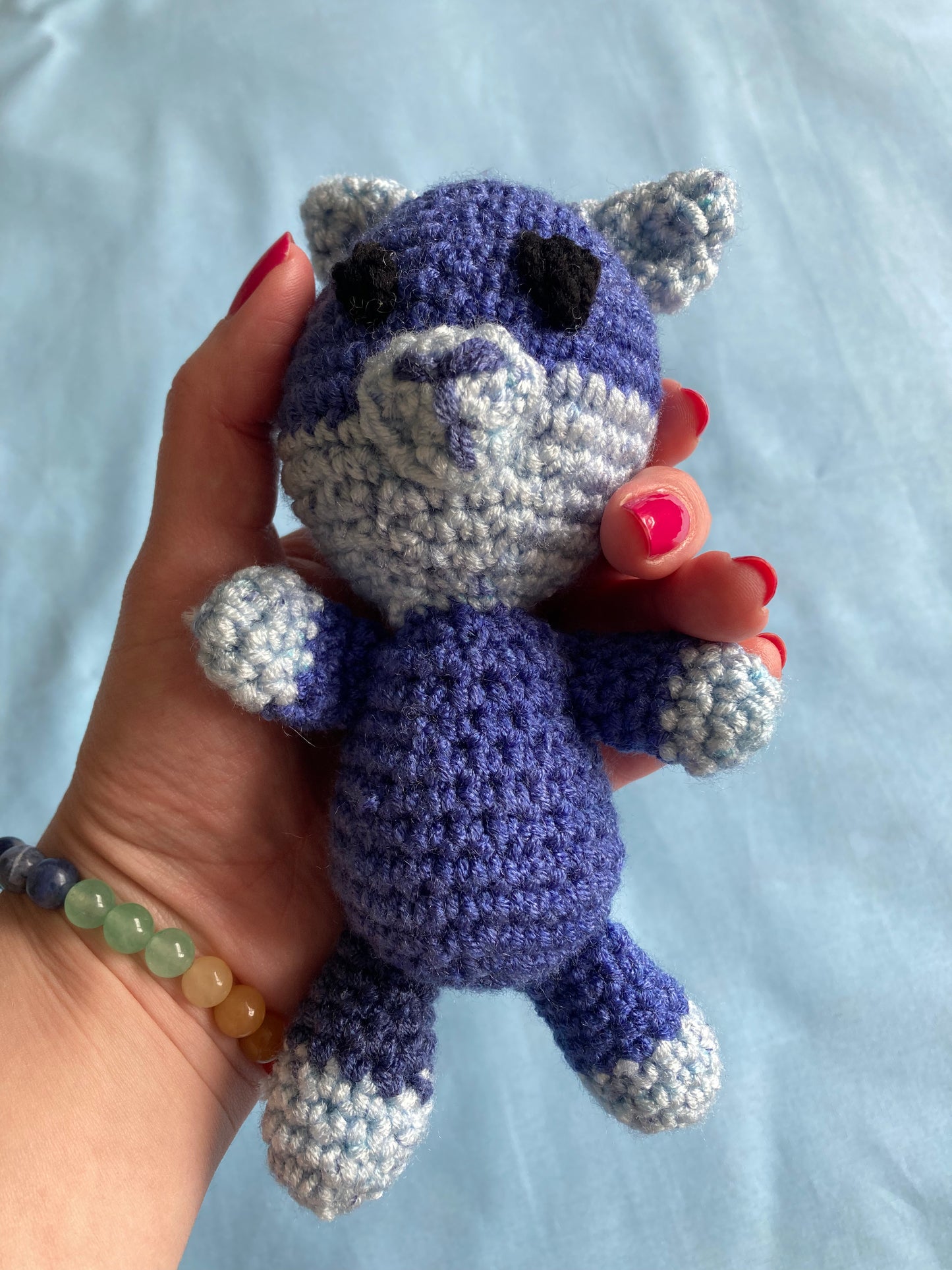 hand holding blue crochet cat