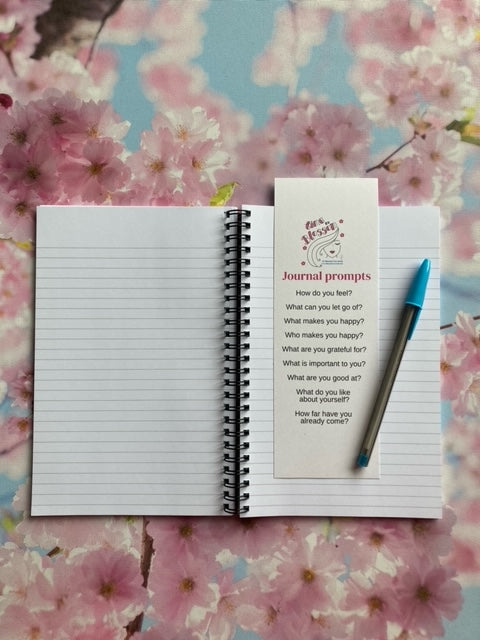 journal, pen and Journal prompt bookmark includes 9 questions, with blossoms in the background