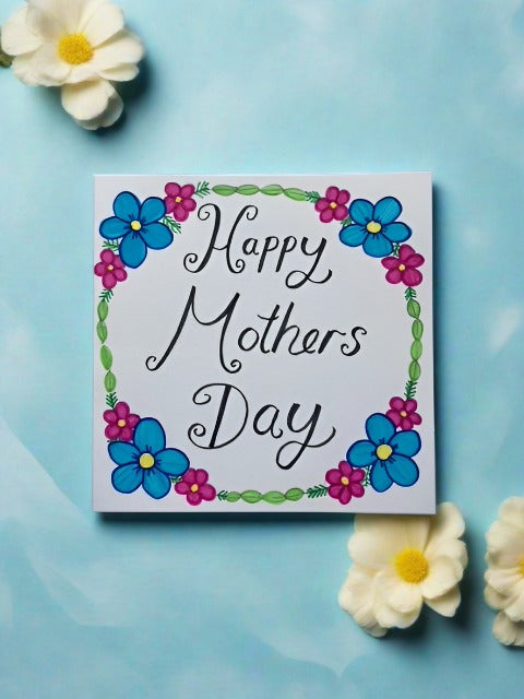 Handmade card with flowers and leaves around the edge of card and writing in the middle that reads happy mothers day