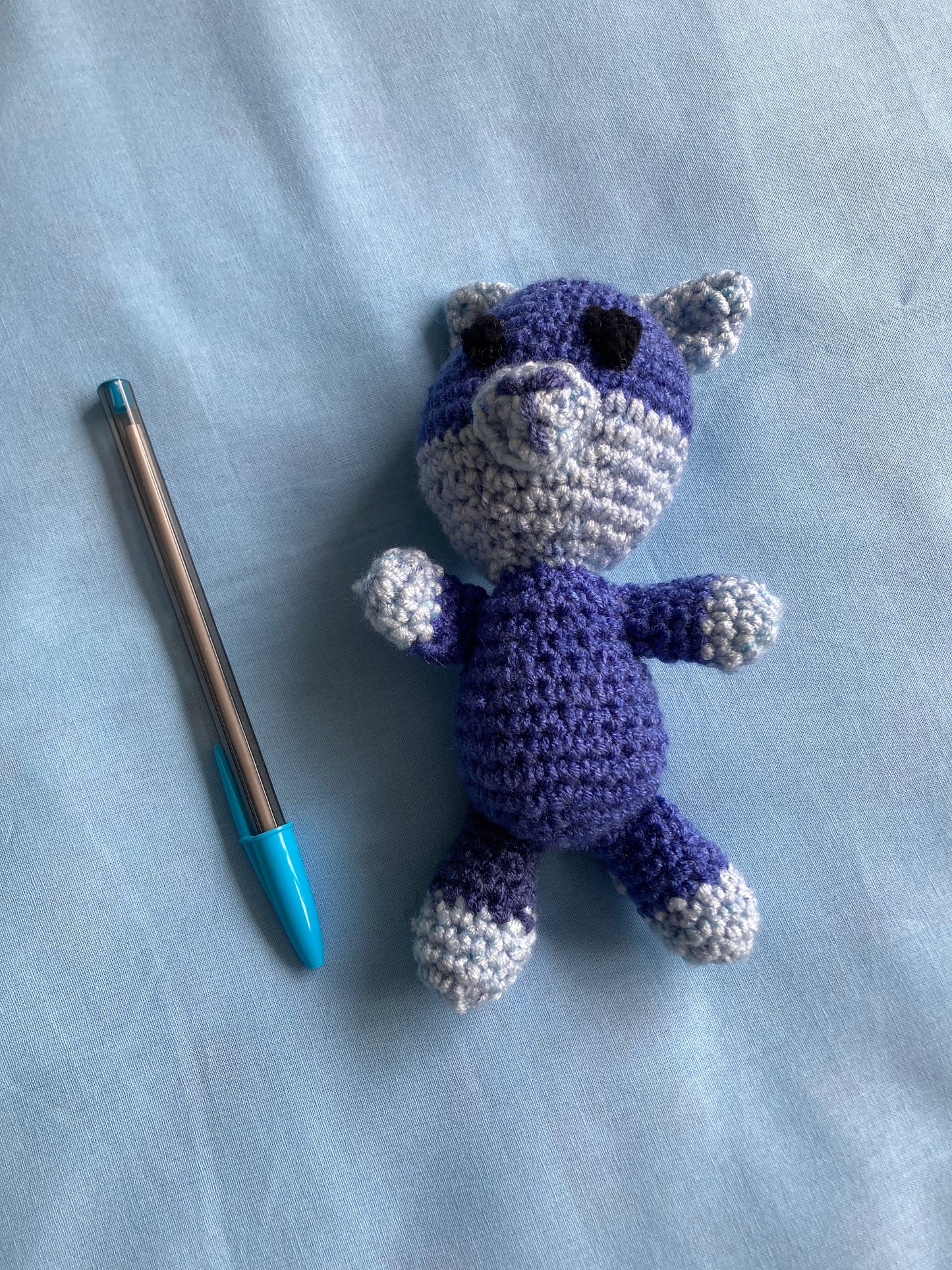 handmade blue crochet cat with pen next to it